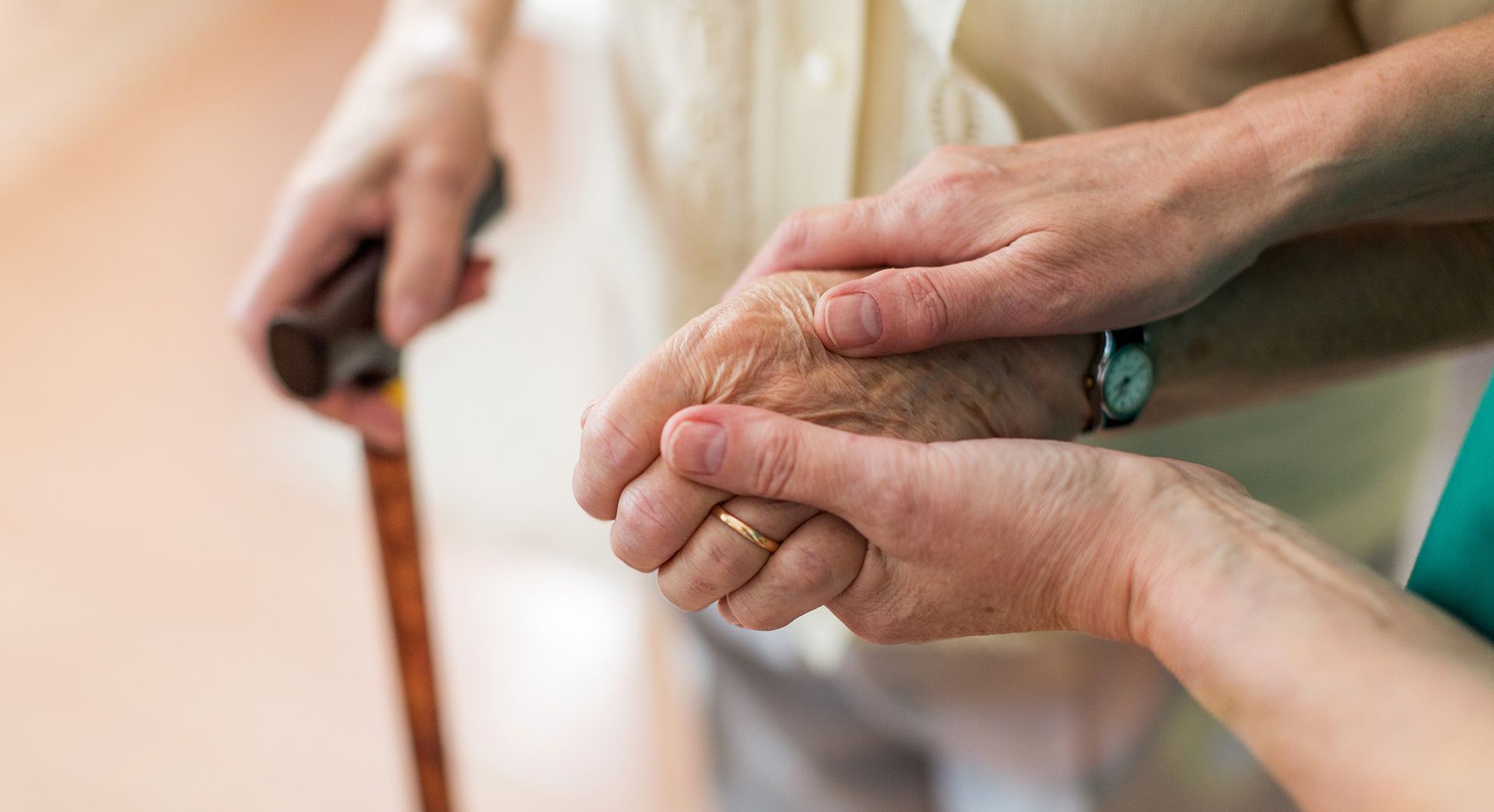 Eine Frau hält eine Hand einer älteren Dame.